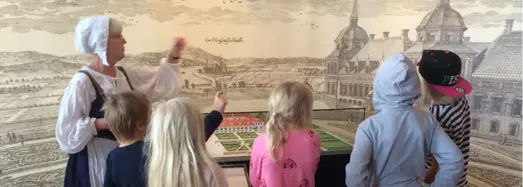 Lärare i gammeldags kläder berättar om Eskilstuna slott för en skolklass